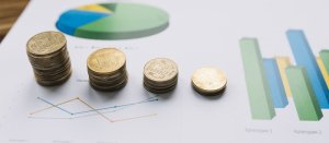 Moedas empilhadas sobre relatórios e gráficos financeiros